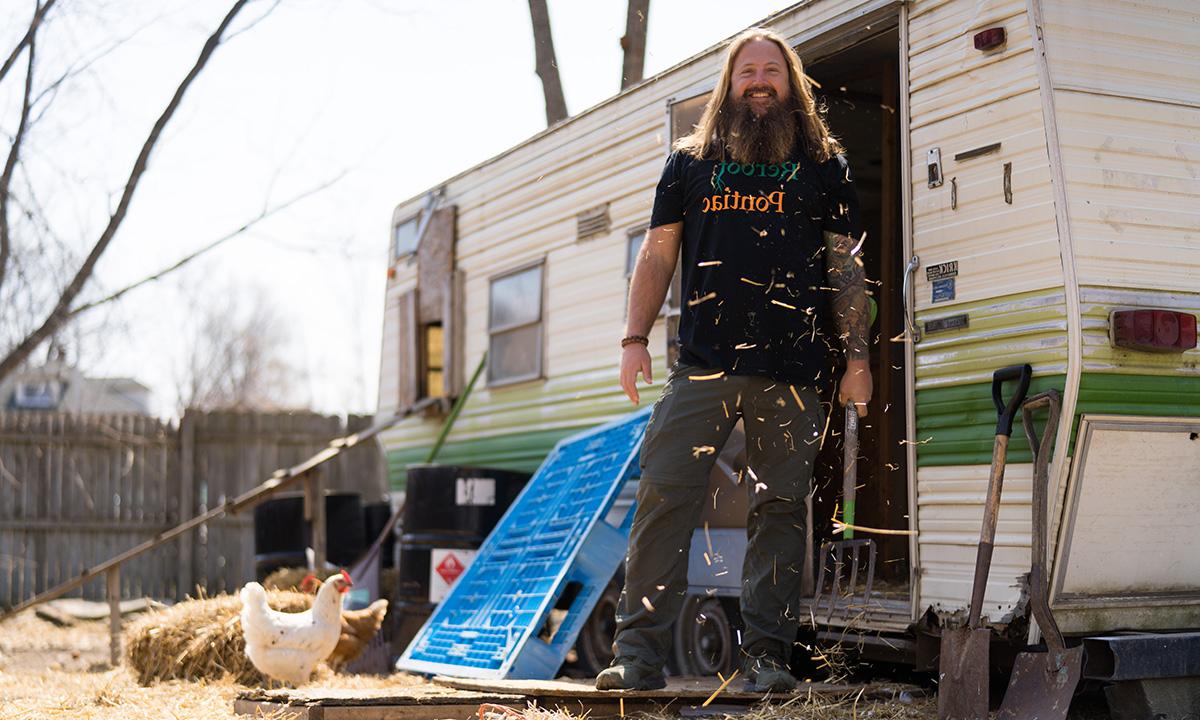 Man standing at trailer with straw and chickens